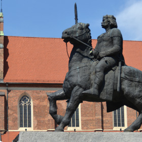 pomnik króla Bolesława I Chrobrego i fragment południowej fasady kościoła